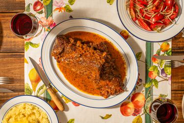 Overhead view of Costillar a la Chilena on a fruit patterened table runner