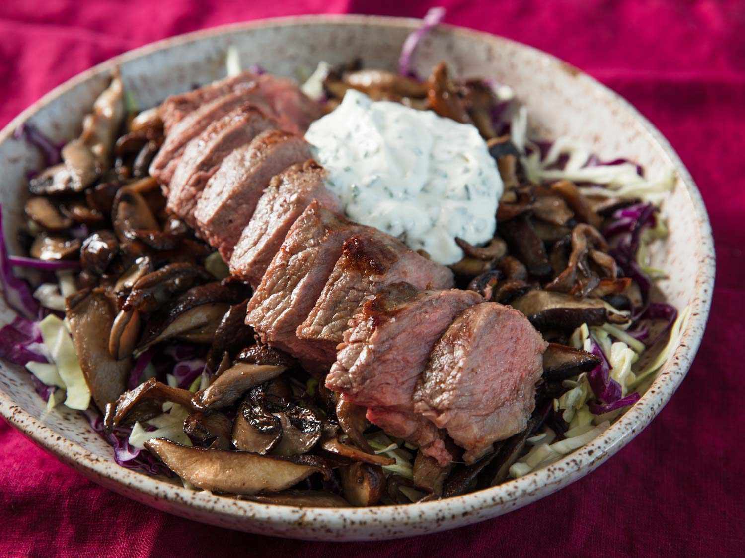Close up strip steak with mushrooms, sour cream and chives, and cabbage slaw on a plate