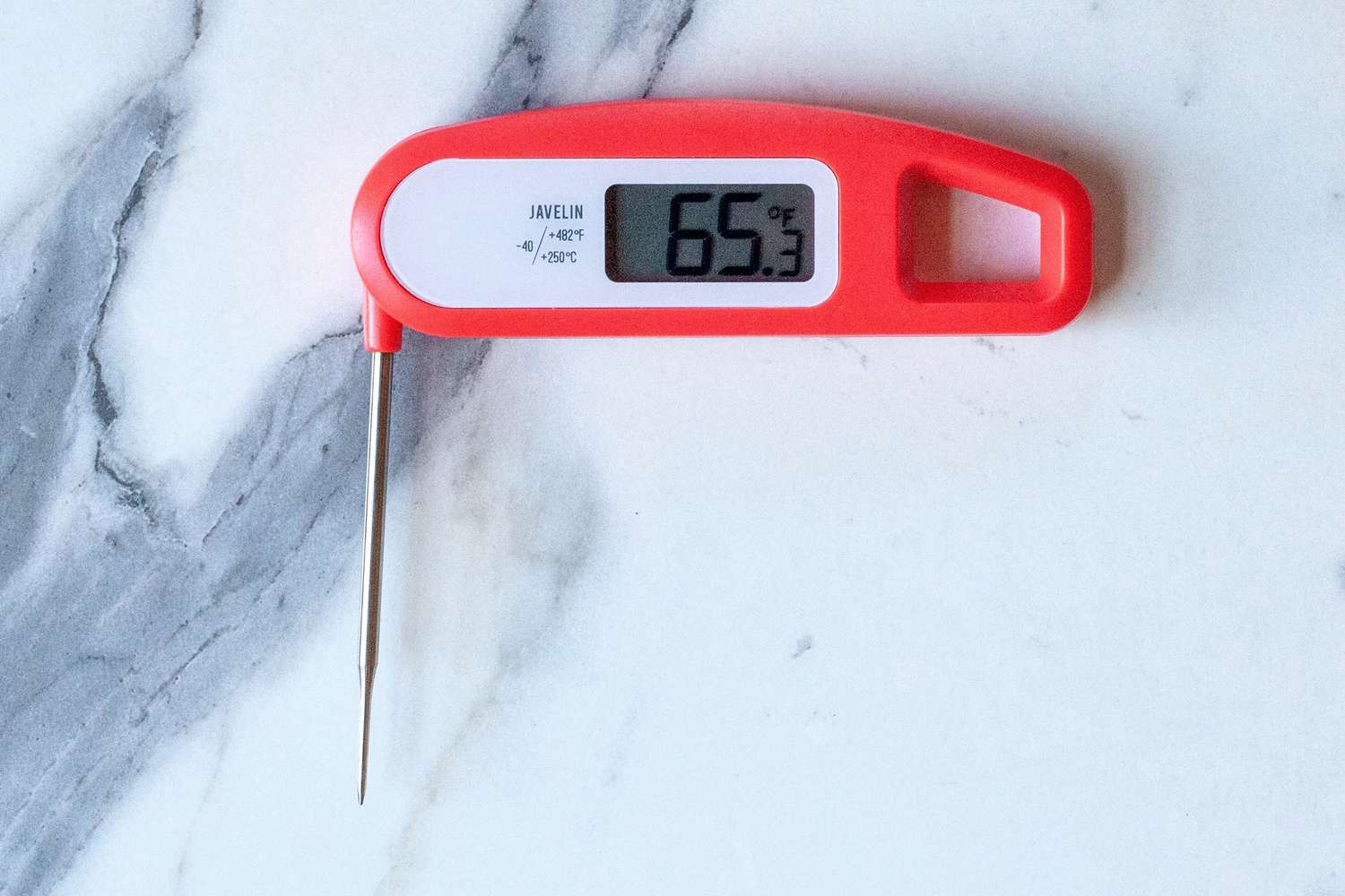 A red instant-read Lavatools thermometer on a marble countertop.