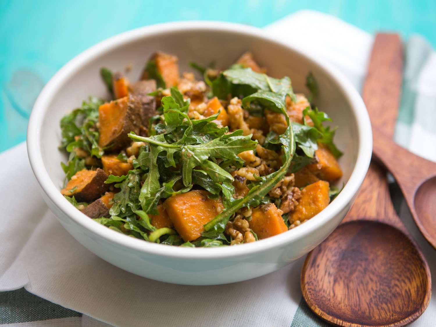 A small white bowl holds a serving of Arugula, Sweet Potato, and Walnut Salad With Dashi "Vinaigrette."
