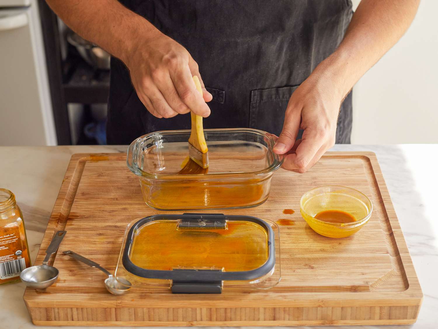 A mixture of oil and turmeric being painted onto a food storage container