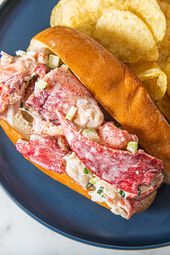 Overhead view of a stuffed lobster roll on a blue plate with potato chips