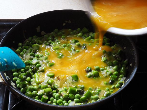 Beaten eggs are stirred into the onion, asparagus, and pea mixture.