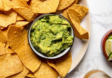 Bowl of guacamole set inside a platter of tortilla chips