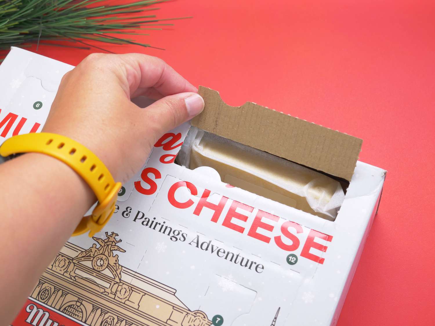 a person opening one of the boxes in the advent calendar to reveal a wedge of cheese. 