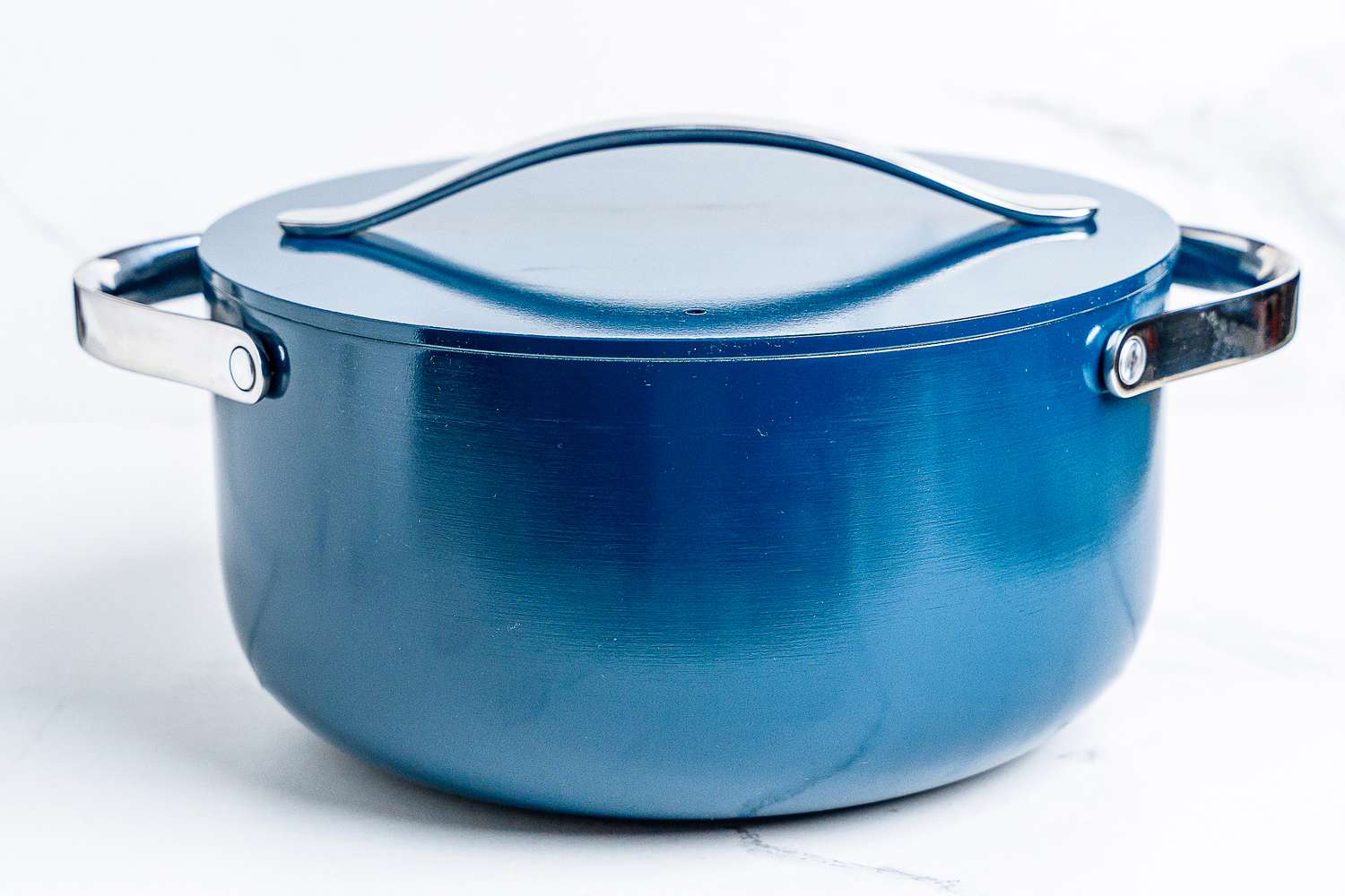 A pot from the Caraway Cookware Set on a white surface