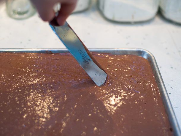 An offset spatula is used to measure the depth of the batter.