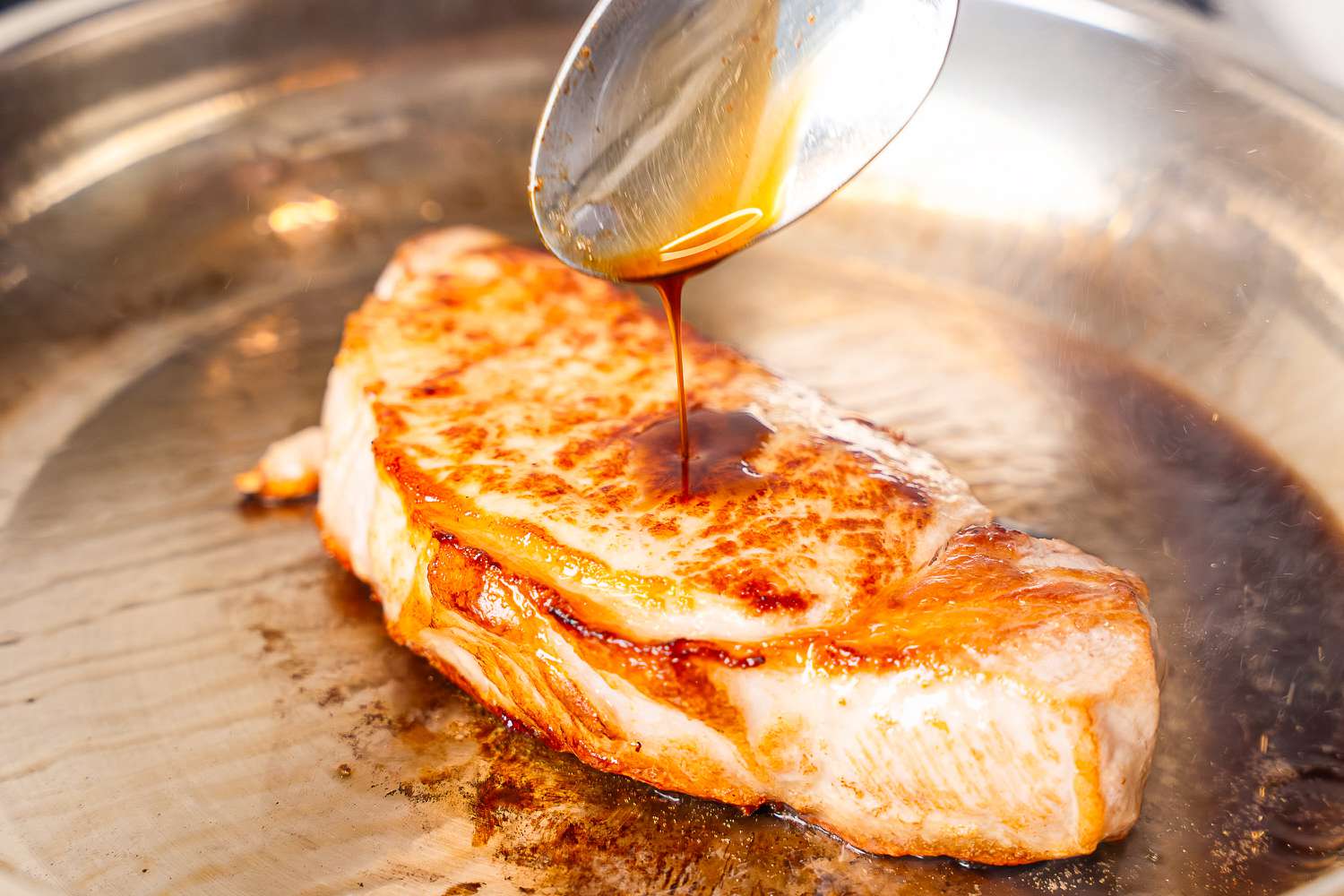 A piece of meat cooking in a pan from the Cuisinart Copper Collection Tri-Ply Cookware 8-Piece Set