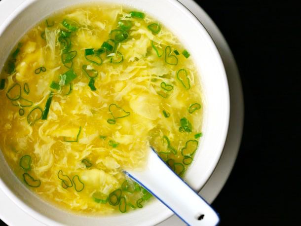 A finished bowl of egg drop soup topped with scallions.