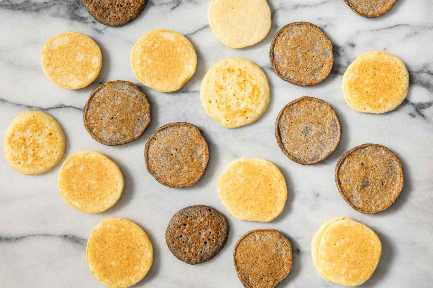 Overhead shot of yeasted and buckwheat blini on marble counter