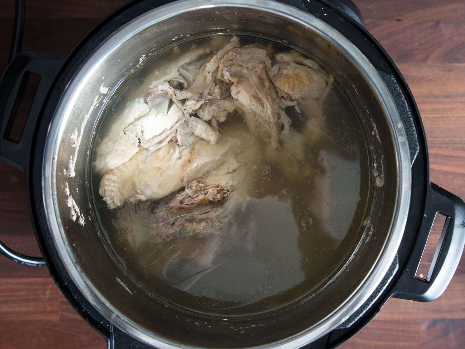 Chicken carcass and broth in pressure cooker after cooking