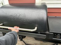 A person lifting the lid of the Traeger Woodrige pellet grill