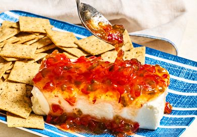Cream cheese topped with pepper jelly, served on a plate with crackers