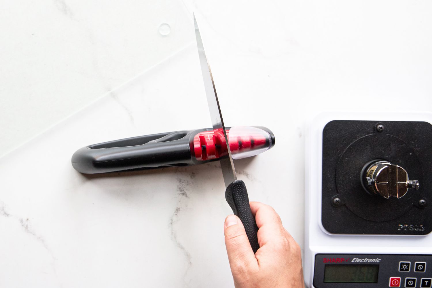 Someone using a knife sharpener applying downward pressure