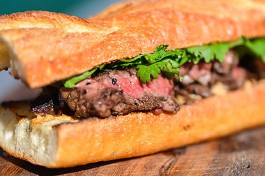 A grilled jalapeño-marinated steak baguette sandwich on a wooden board