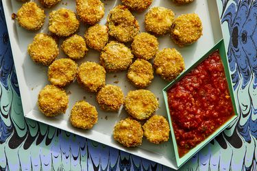 Finished jalapeno poppers on a plastic tray with a funky background and red dipping sauce