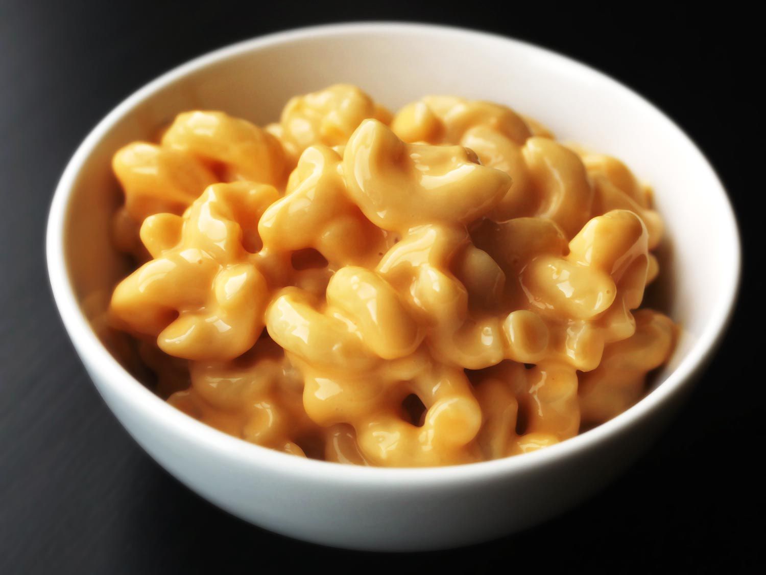 A bowl of ultra-gooey macaroni and cheese in a white bowl.