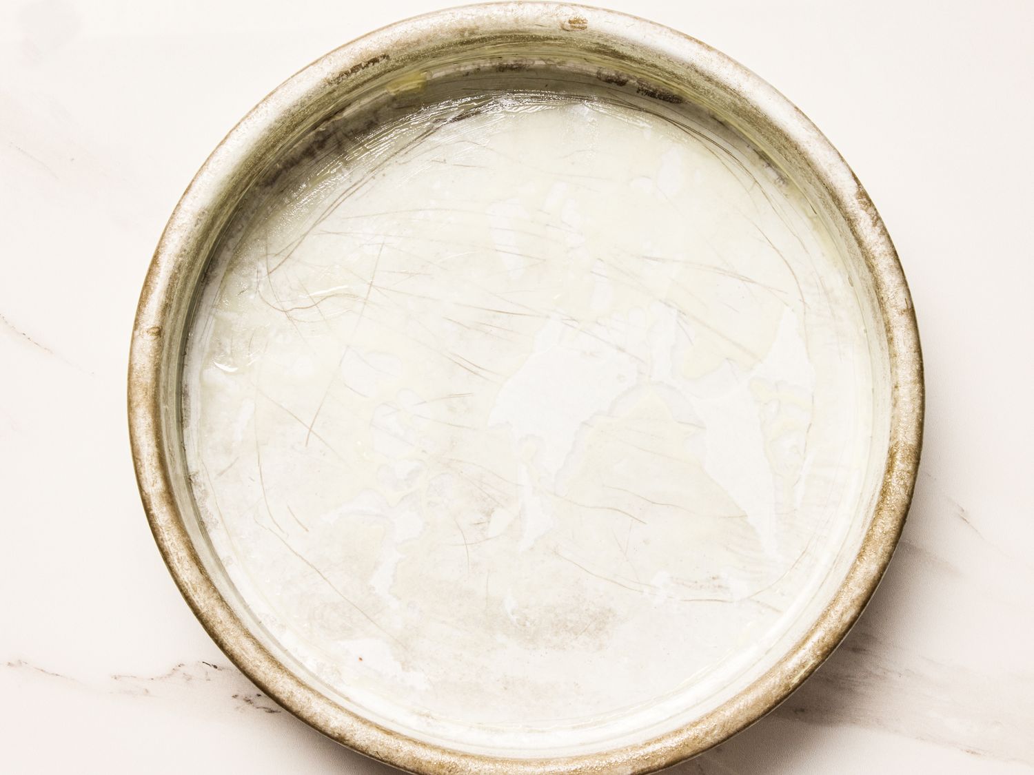 A round cake pan coated and prepared for baking