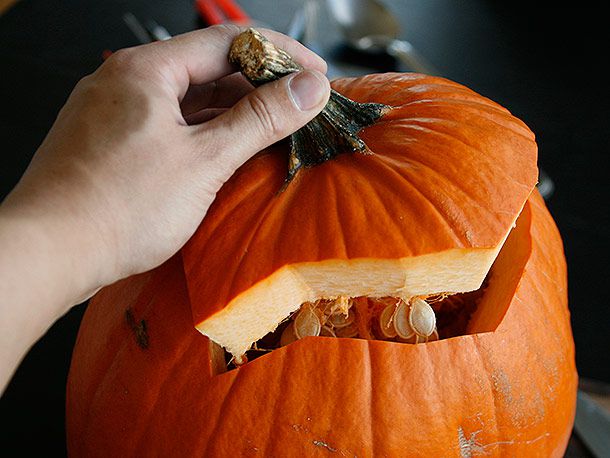 Removing the lid from a pumpkin being prepped for carving