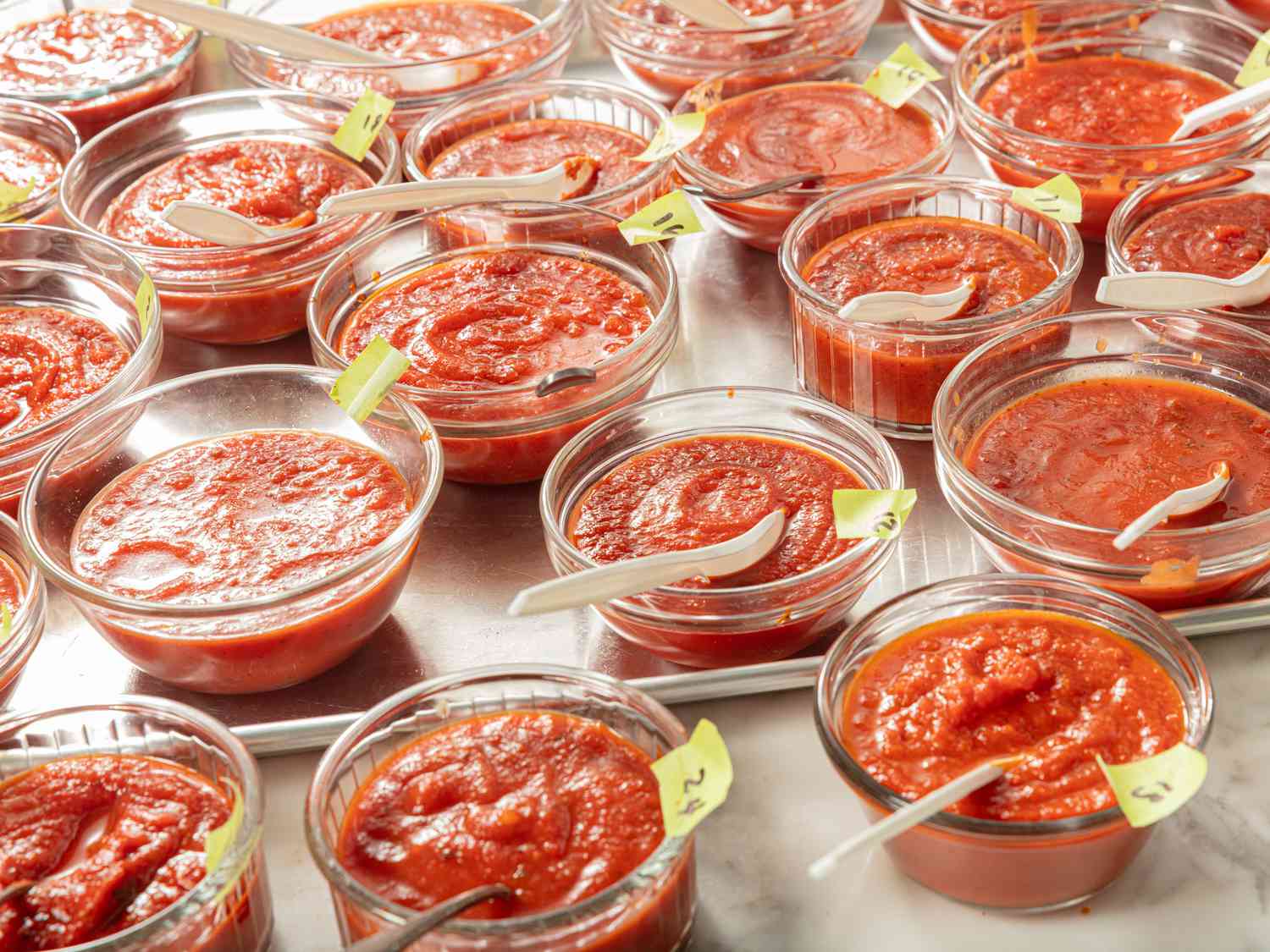 small bowls lined up with different marinara sauces in them, with numbers and spoons on each bowl 