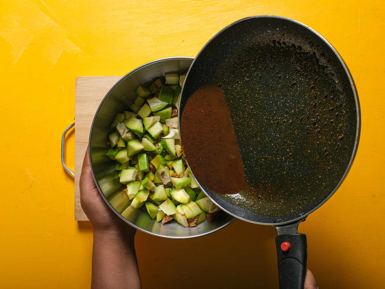 Adding pickle juice into bowl of mango from pan 