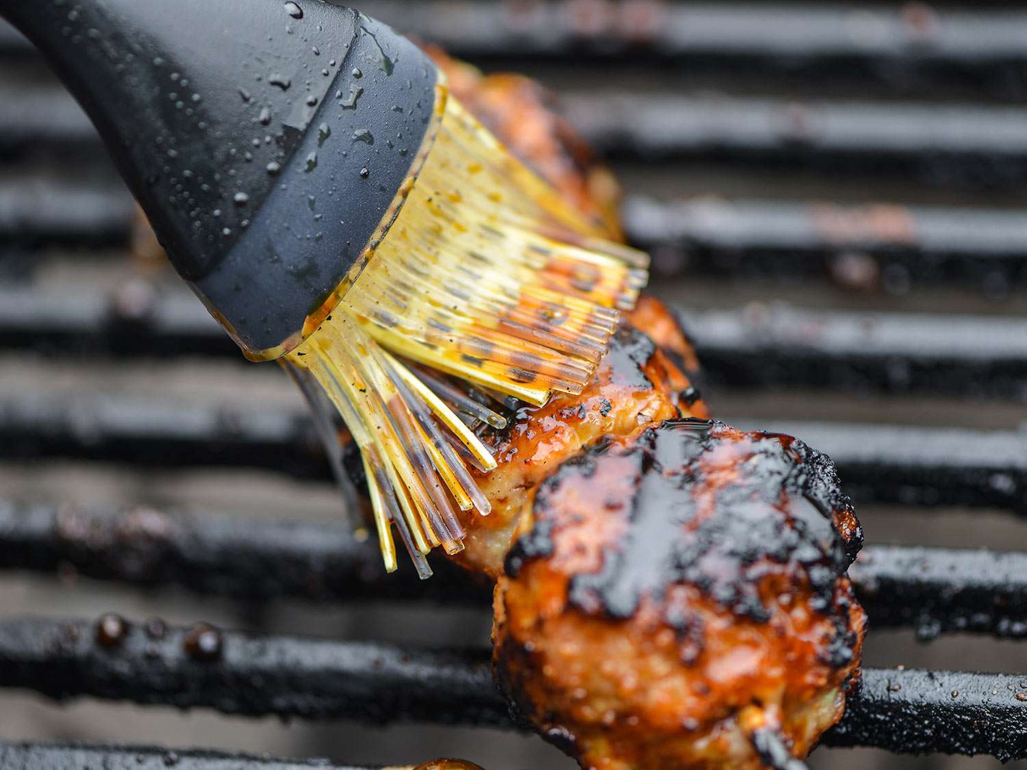 Brushing tare sauce over a skewer of Japanese chicken meatballs.