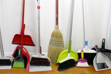 a variety of kitchen brooms leaning against a wall