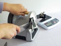 a person sharpening a knife on a spinning knife sharpener
