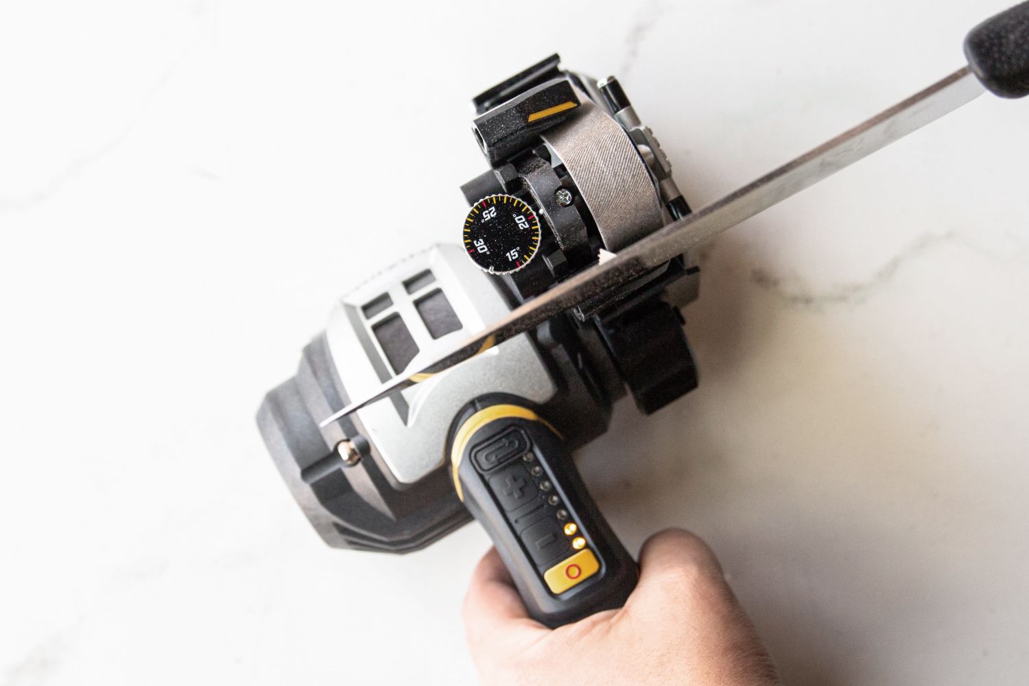 An overhead view of a person using an electric knife sharpener