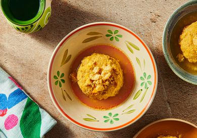 Bowl of Mofongo from above in a bone colored dish with flowers on it, and edges of other bowls of mofongo on the bottom rightside. 