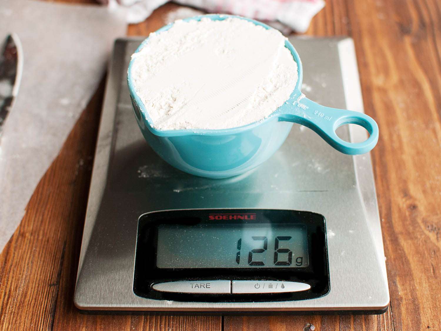 The measuring cup of spooned flour weighs 126 grams.