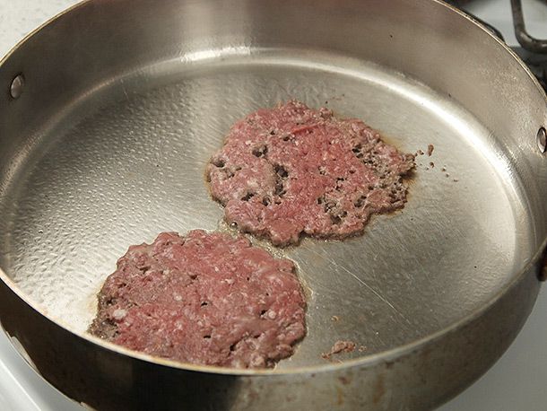 Two smash beef patties in stainless steel skillet