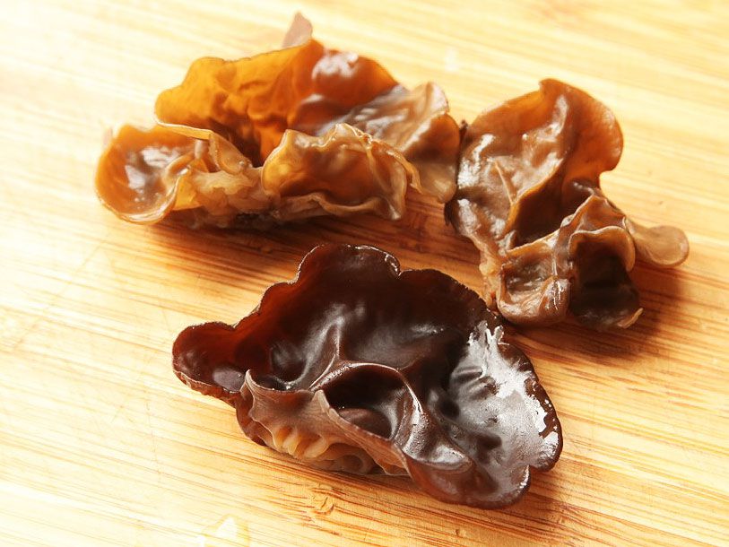 Three wood ear mushrooms resting on a cutting board.