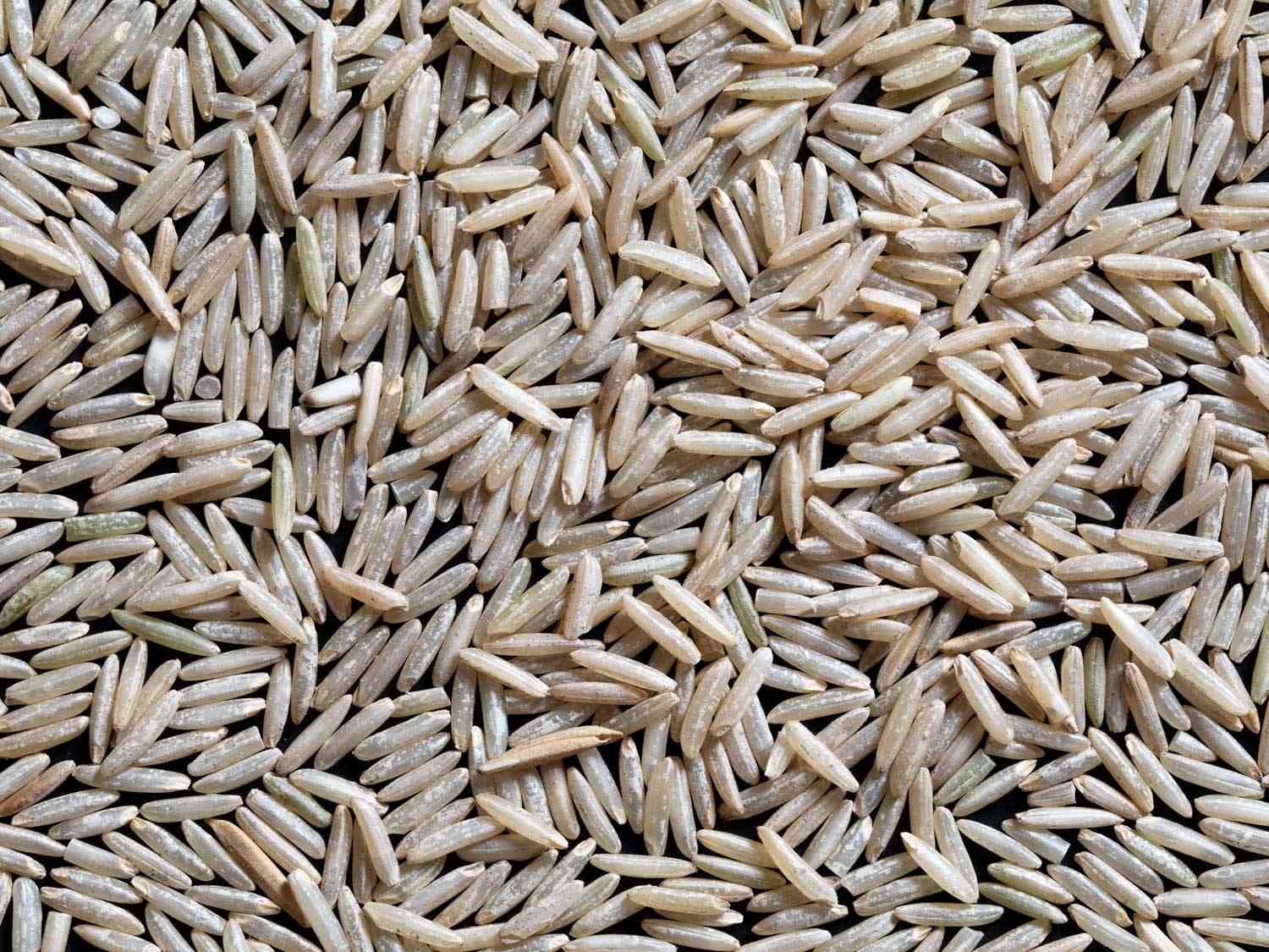 Overhead close-up of long brown basmati rice grains on a flat surface.