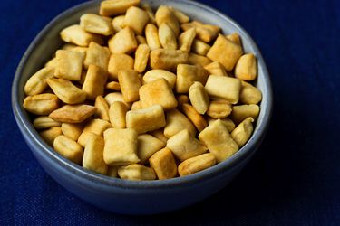 A blue ceramic bowl of DIY oyster crackers on a blue cloth.