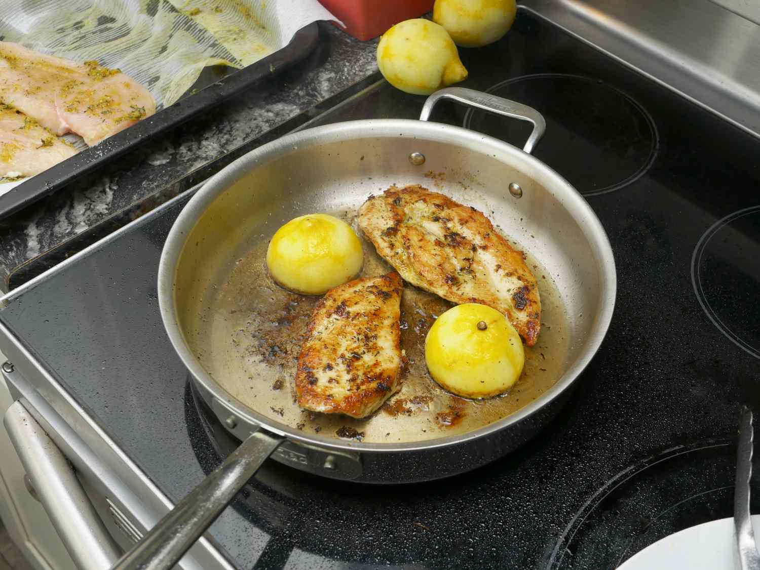 a saute pan with chicken and lemons inside