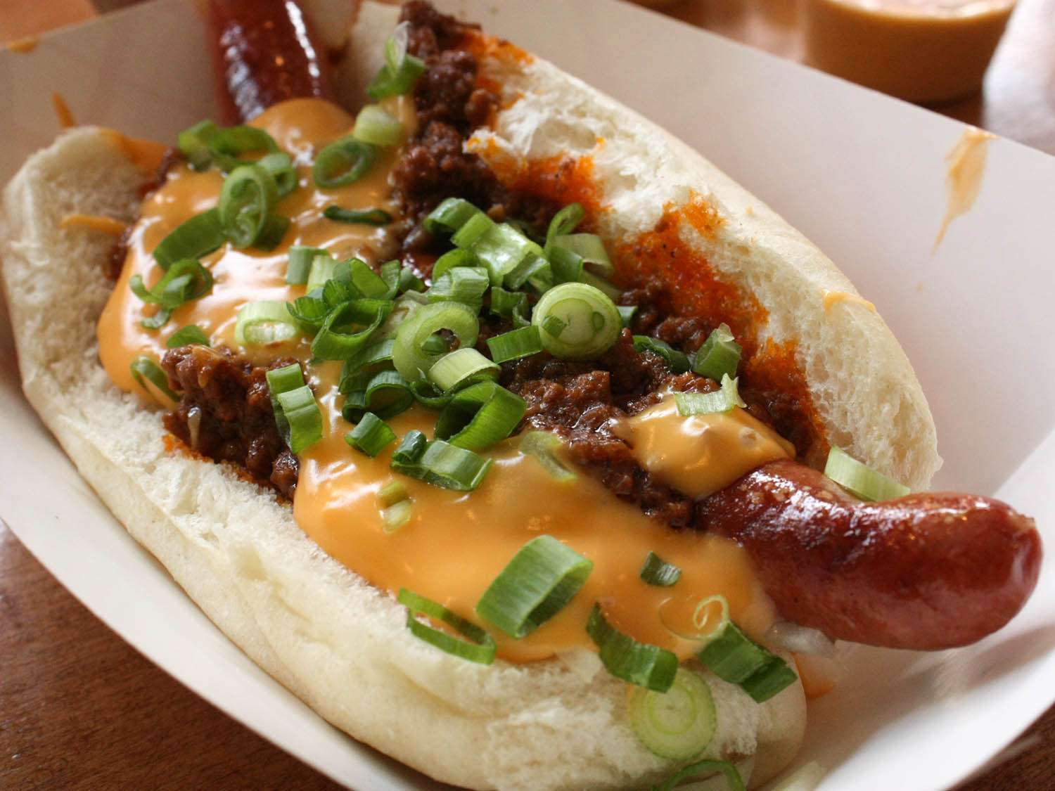 A chili-cheese dog topped with scallions.