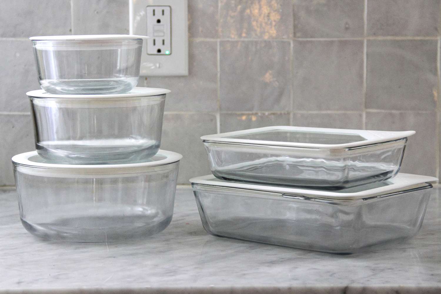 Pyrex Ultimate 10-Piece Glass Storage Set with lids on a marble countertop in front of a tiled wall