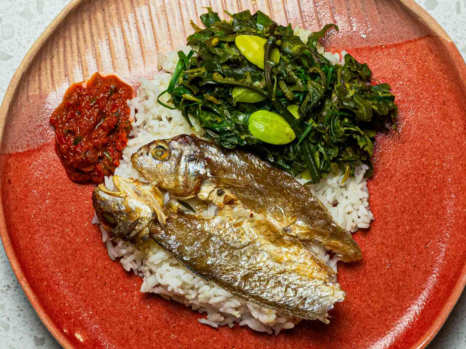 Grilled fish on white rice with fiddleheads and favas and a dollop of sambal on the side.