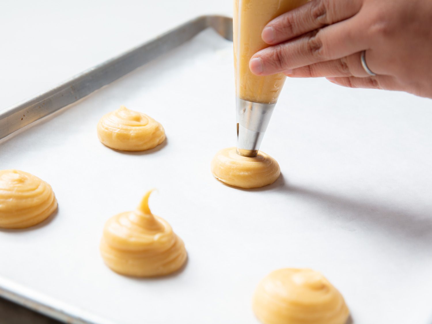 piping choux onto a baking sheet