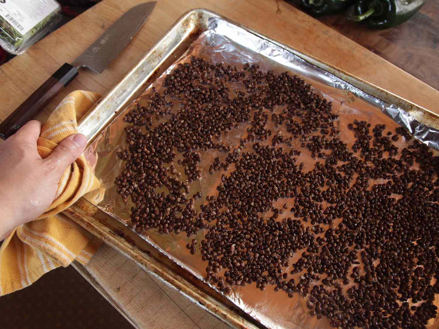 Lentils on a rimmed baking sheet lined with foil, ready for the oven.