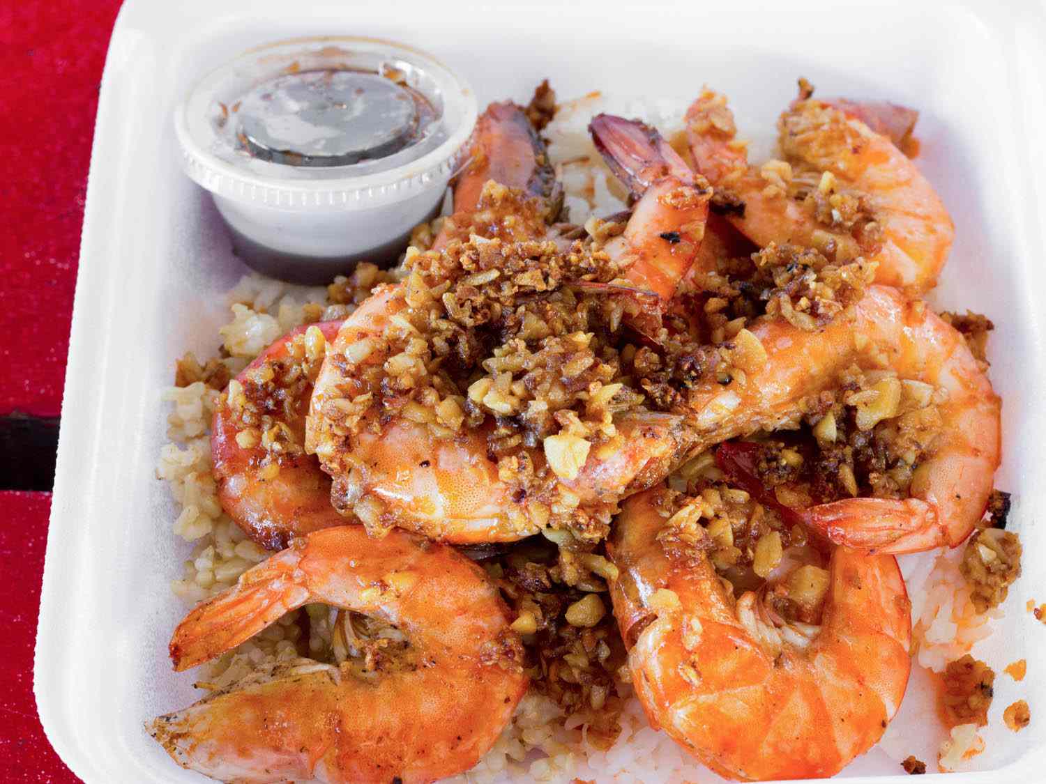 An order of garlic shrimp in a takeout container.