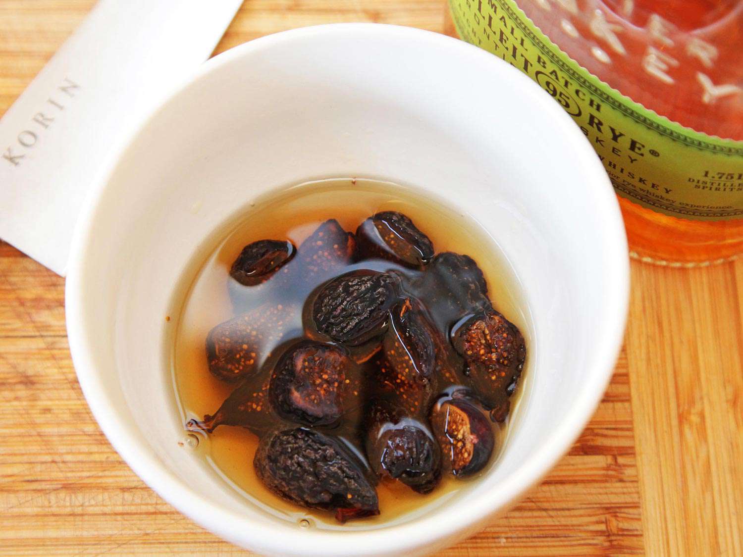 Figs soaking in a bowl containing bourbon. 