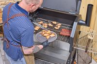 A person cooks chicken wings in the Yoder Smokers YS640S Pellet Grill