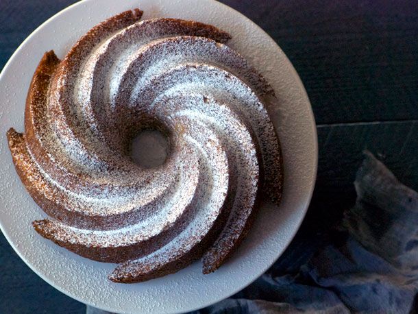 Overhead view of a pudín Mary cake, served on a white plate and dusted with confectioners' sugar.