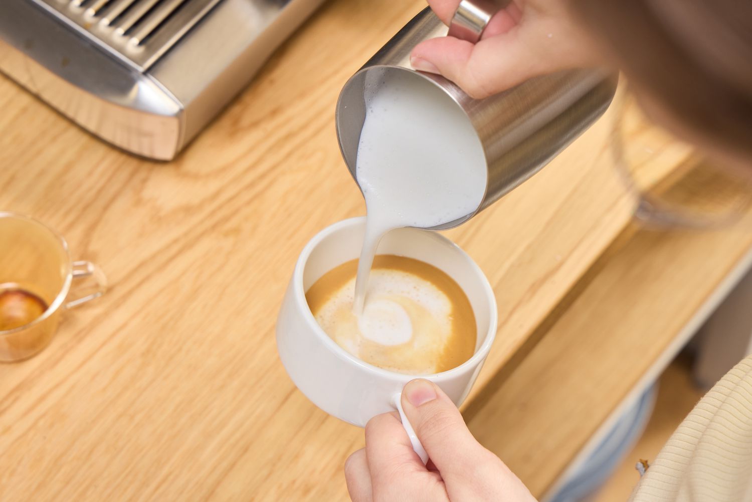 A person makes a capuccino using the Breville BES920XL Dual Boiler Espresso Machine