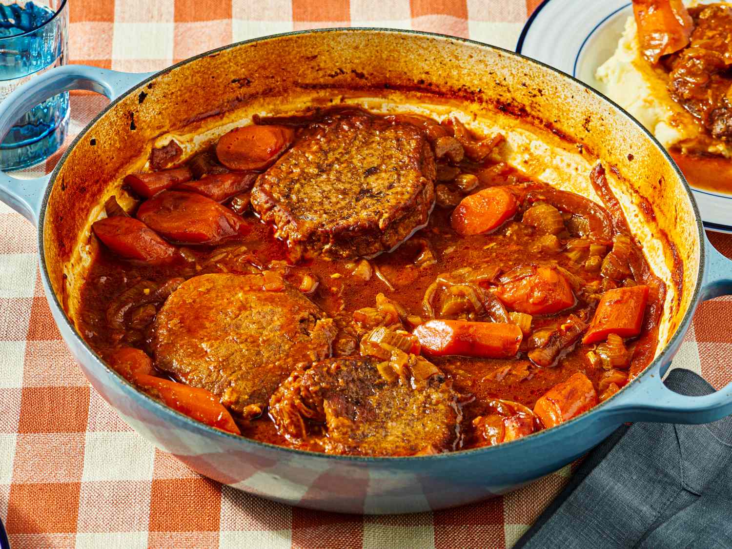 Swiss steak with carrots and tomato sauce in a blue dutch oven
