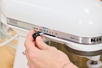 A person adjusts the speed of the KitchenAid 5-Quart KSM150PSER Artisan Stand Mixer