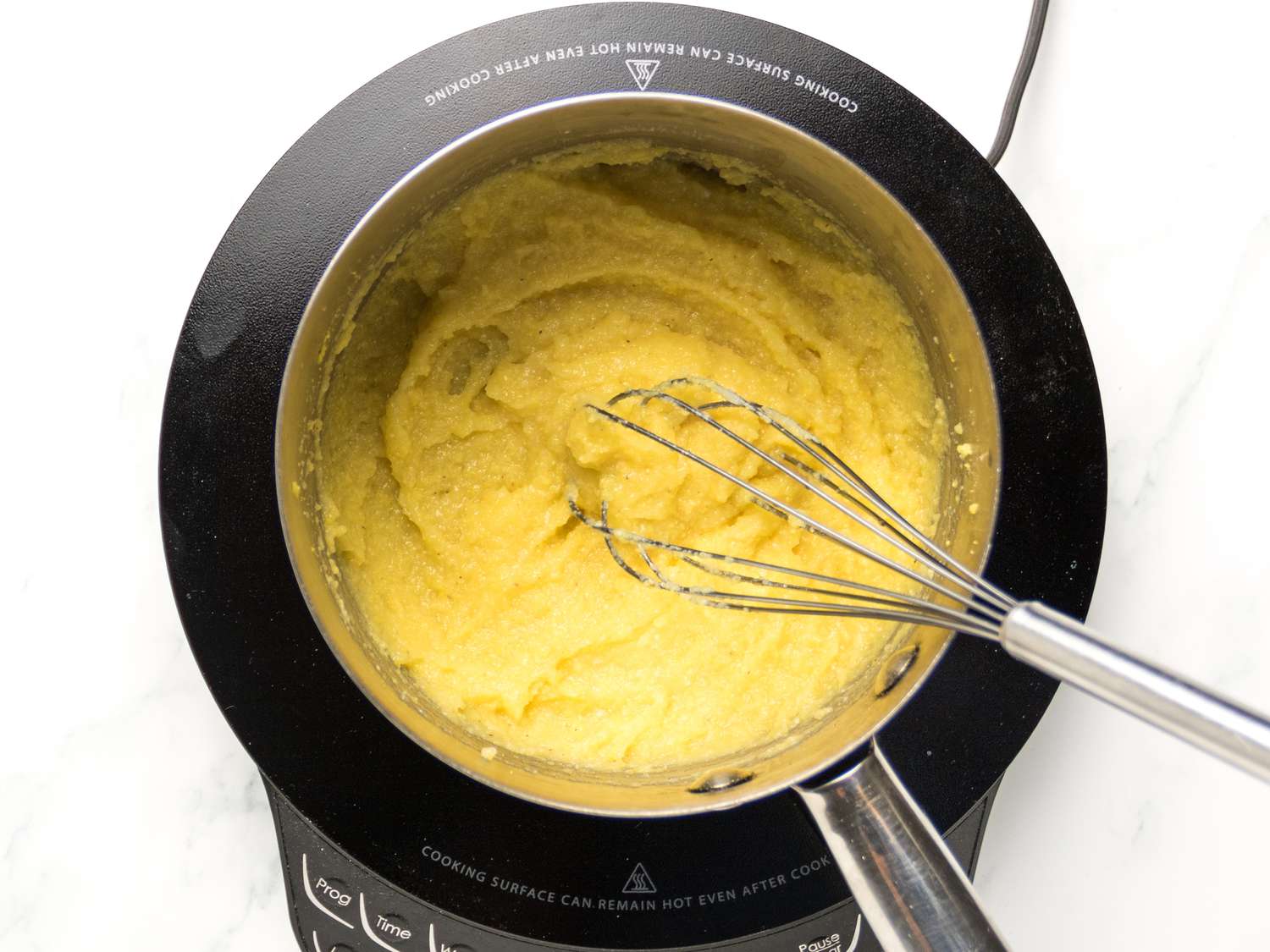 whisking cornmeal into water on heat in a saucepan