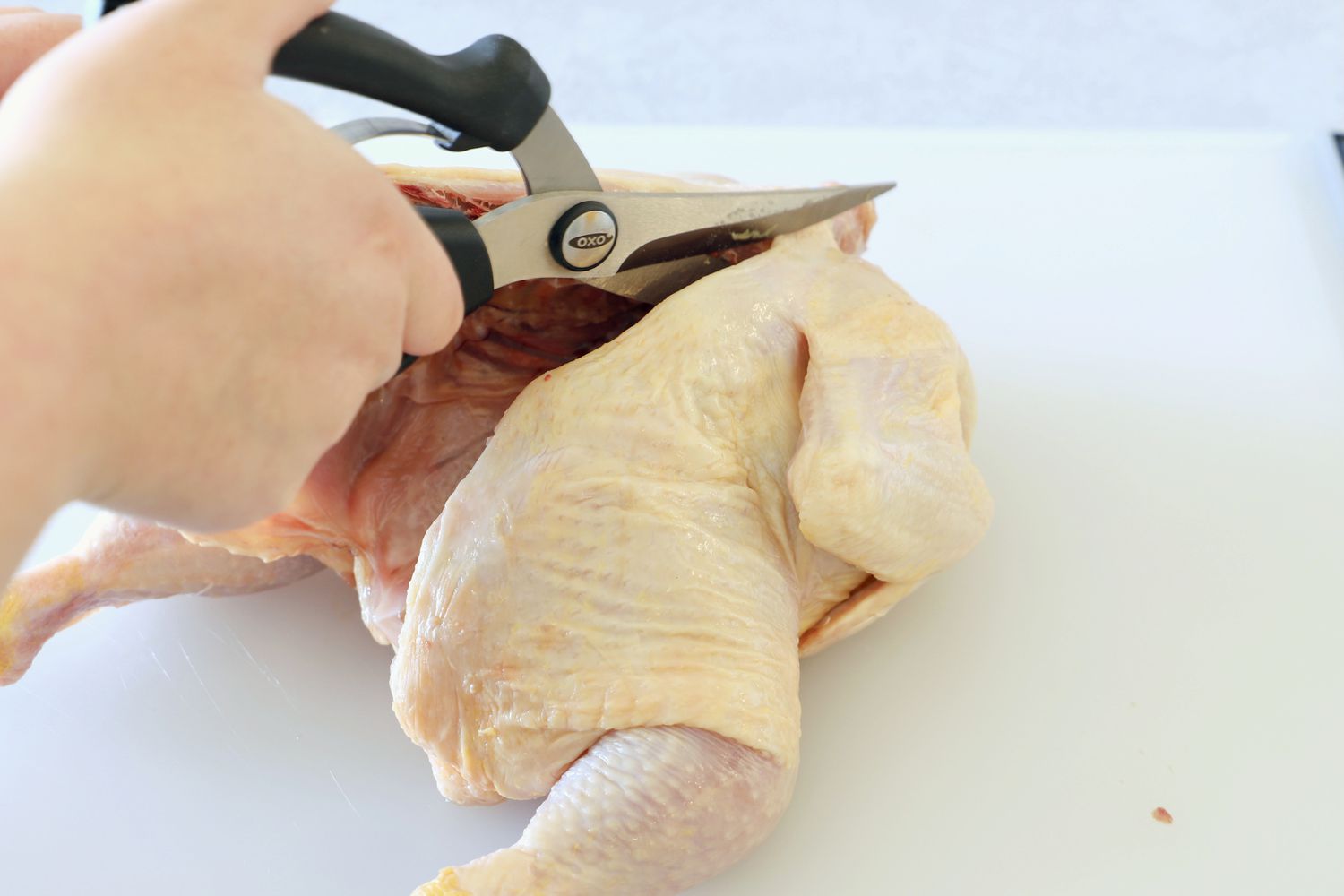 Using poultry shears to remove a chicken's backbone.